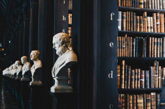 library with rows of black book shelves and bust statues