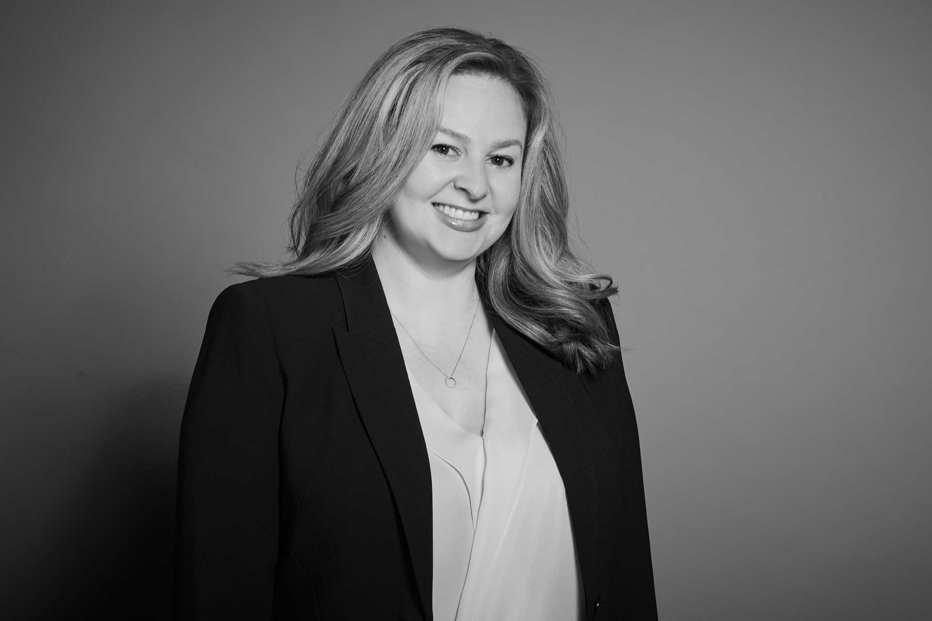 black and white adrianne graves with long blond hair smiling and wearing suit